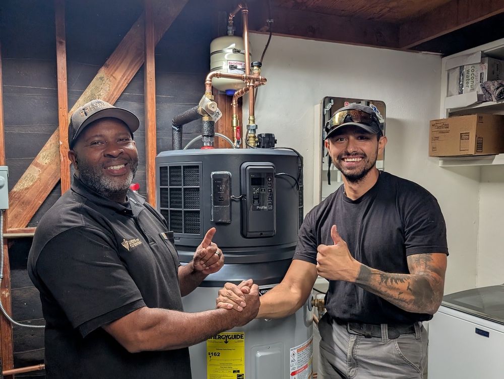 Two installers shaking hands in front of a newly installed heat pump water heater